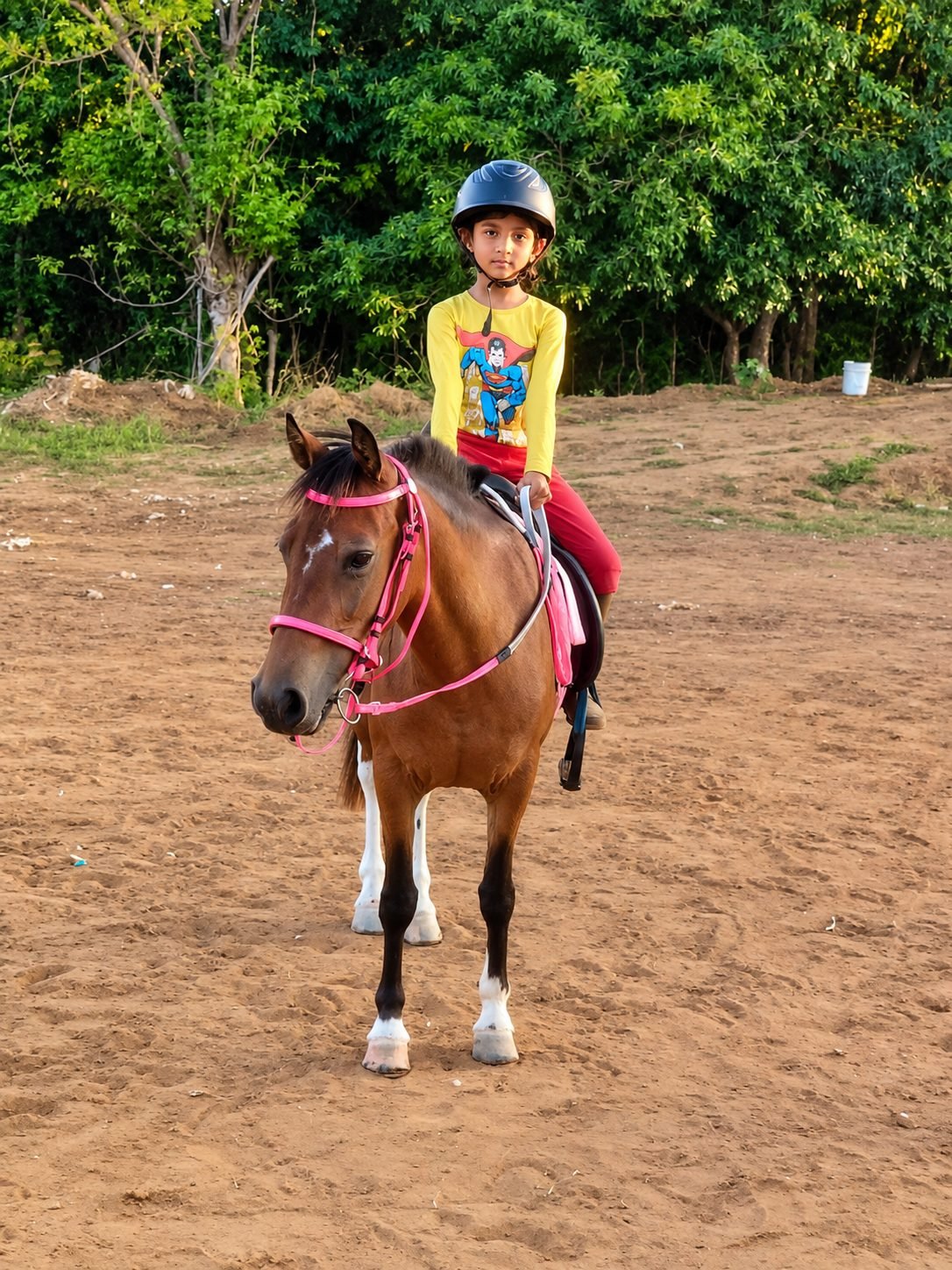 Child in riding helmet on a pony during training at Shri Surya Horse Riding Training Centre